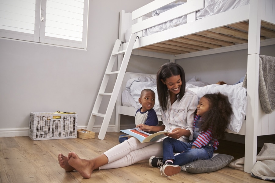 Mother Reading Story To Children In Their clean Bedroom.